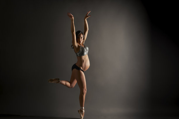 年轻的西班牙怀孕芭蕾舞演员表演古典芭蕾姿势与亮片顶部在工作室图片下载