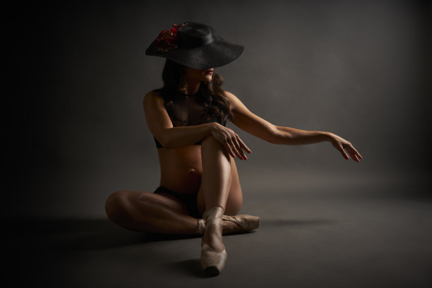 年轻的西班牙怀孕舞者摆造型与帽子和黑色内衣在工作室图片下载
