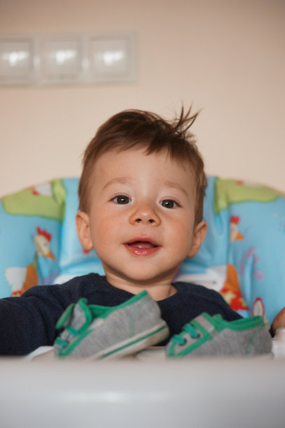 一个可爱的快乐的男孩坐在高婴儿椅特写图片下载