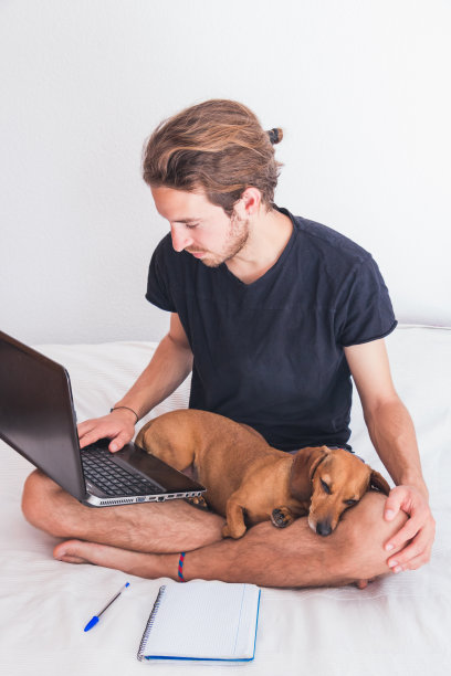 年轻人带着狗在工作图片下载