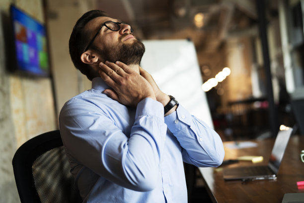 一个男人坐在办公室里用笔记本电脑工作。图片下载