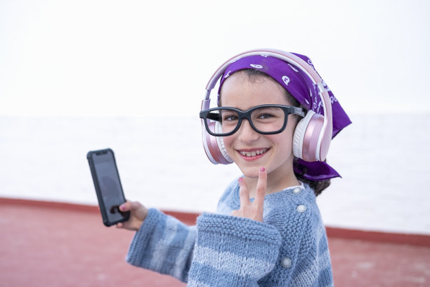白人小女孩戴着耳机和眼镜自拍图片下载