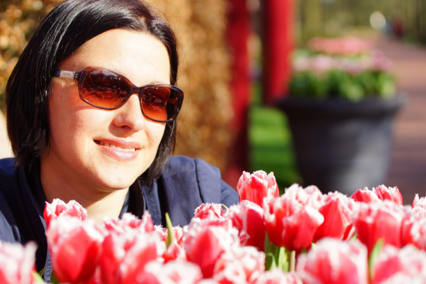 一名白人女性坐在一群红色郁金香后面图片下载
