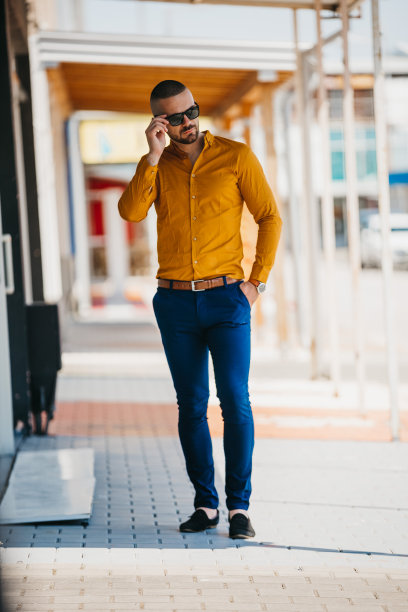 酷帅的白人男子穿着优雅的芥末衬衫和太阳镜摆出户外图片下载