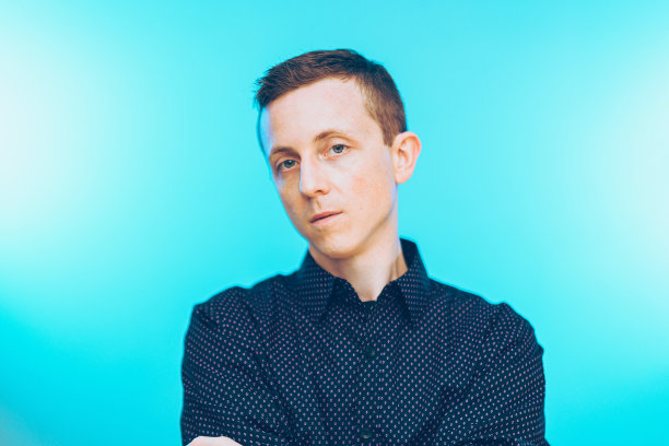 一名穿着衬衫的美国男子在蓝色渐变背景上摆姿势图片下载