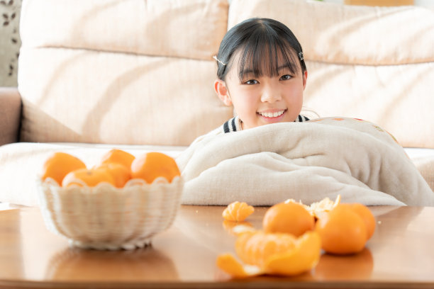 一个亚洲女人在客厅的烧饼上吃橘子图片下载