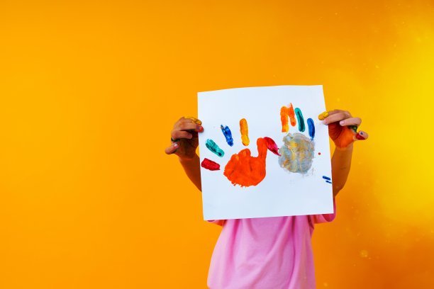 年轻的孩子拿着黄色背景的纸艺术图片下载