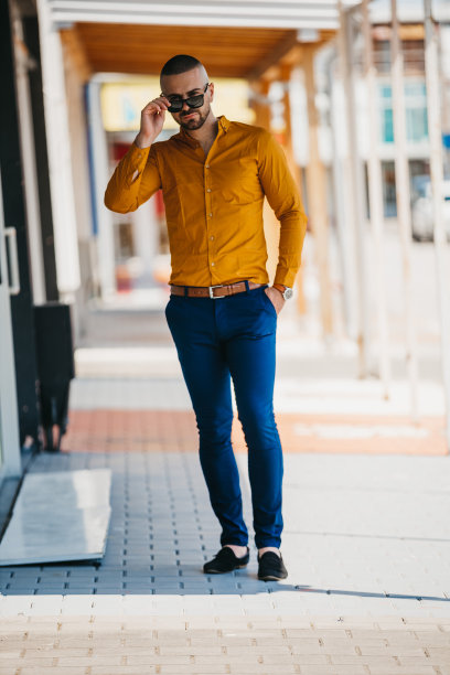 酷帅的白人男子穿着优雅的芥末衬衫和太阳镜摆出户外图片下载