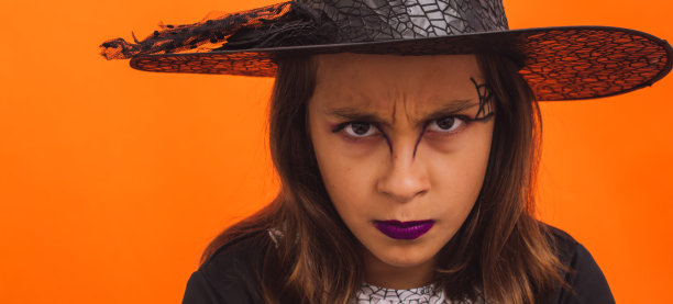 白人女孩子穿着橙色背景的女巫服装图片下载