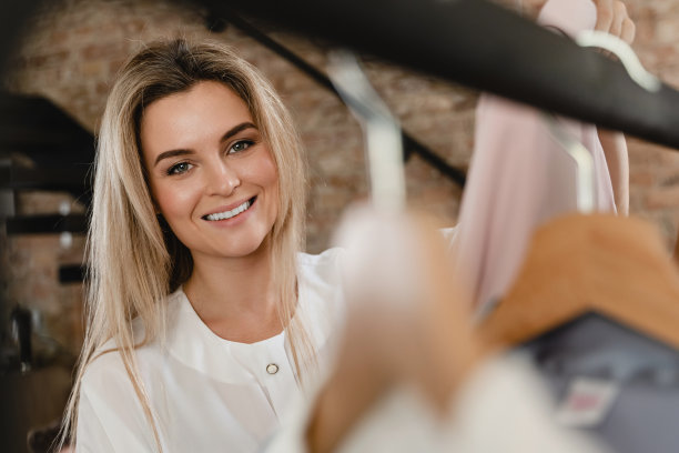 快乐的女人正在浏览她挂在衣柜衣架上的各种衣服图片下载