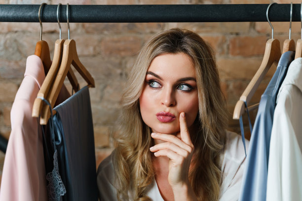 年轻漂亮的女人和衣架与不同的服装图片下载