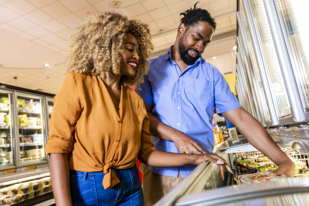 一对非裔美国夫妇推着手推车在购物中心购买杂货图片下载