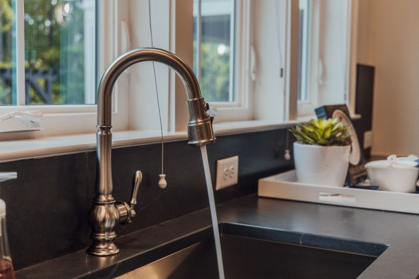 厨房水槽的现代金色水龙头特写，背景模糊图片下载
