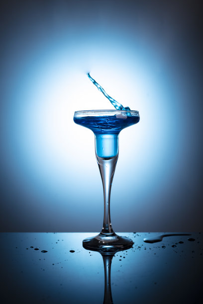 鸡尾酒杯，蓝色背景和背光上有冰块图片下载