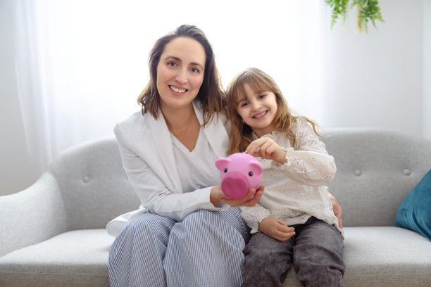 母亲和女儿把硬币放进储蓄罐图片下载