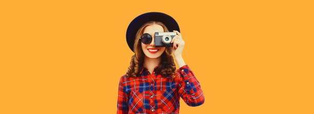 快乐微笑的年轻女子摄影师的肖像与电影相机在橙色的背景，空白复制空间的广告文字图片下载