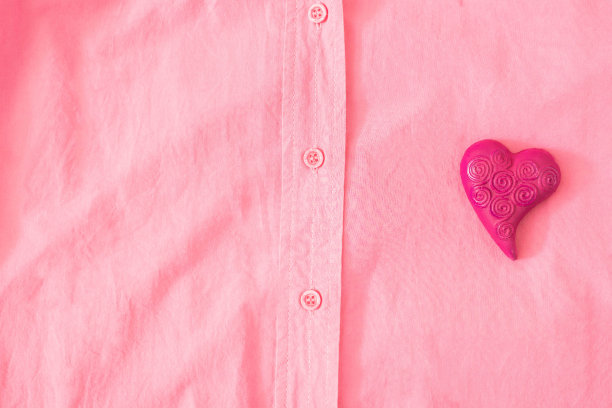 粉色衬衫上有一颗品红的心。最小的超现实概念的情人节横幅或卡片。服装广告设计。平躺图片下载