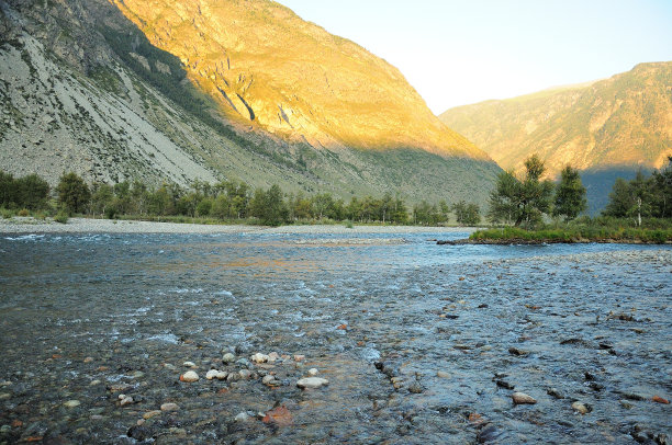 在山后落日的阴影下，一条美丽的浅河在深峡谷中流淌。图片下载
