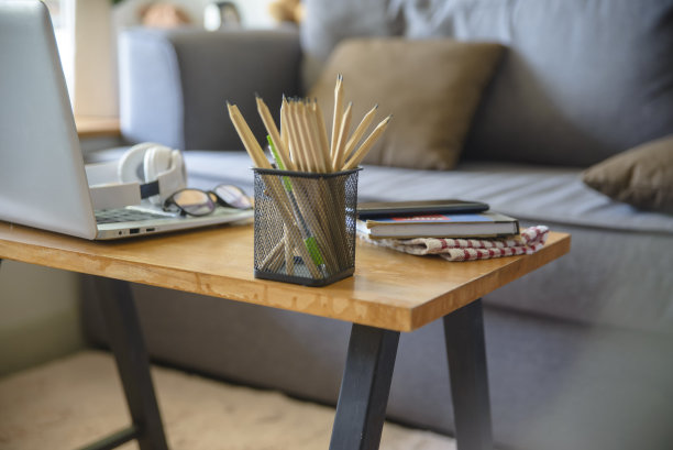 书桌为学生教育理念。铅笔，笔记本电脑，书，时钟和铅笔的学习考试放在木制的学校桌子和舒适的沙发，学生计划在家工作。图片下载