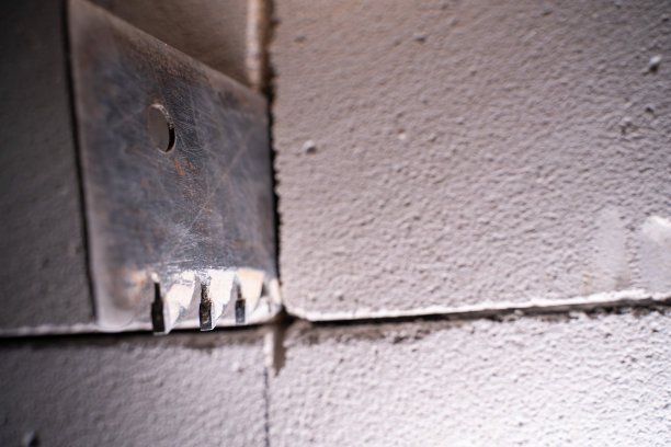 用手锯从掺气混凝土块上切割墙壁的过程，用于掺气混凝土在模糊背景上的特写。重建房屋，在墙上开个门洞图片下载