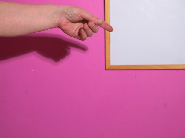 双手指向墙角有白板的洋红色墙壁图片下载