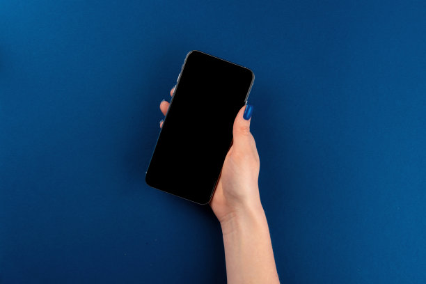女人手拿着智能手机，黑色屏幕和经典的蓝色背景图片下载