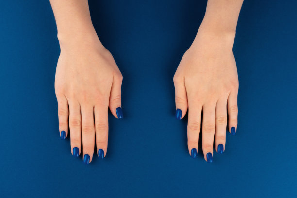 女性手与美甲的经典蓝色蓝色的蓝色背景图片下载