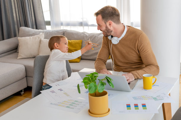 白人男子在笔记本电脑上远程工作，和他的儿子一起玩图片下载
