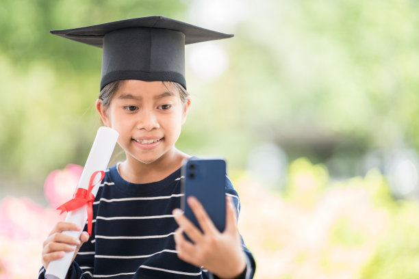 快乐的东南亚女学生在泰国毕业时拿着证书和智能手机图片下载