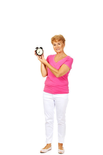 全身照，一位波兰老妇人穿着夏装，展示她的闹钟，孤立在白色图片下载