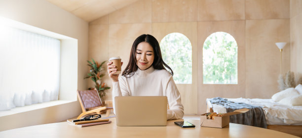 肖像中小企业业务亚洲妇女从家里工作在网上电脑桌面桌子手握咖啡杯。亚洲自由职业者女孩在卧室使用笔记本电脑。中小企业数字化网络技术。图片下载