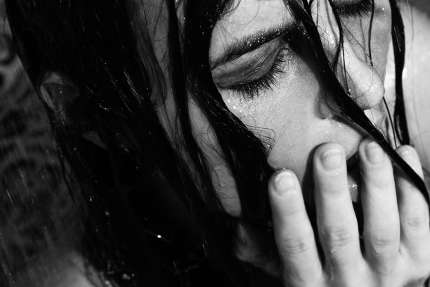 悲伤和潮湿的女人，她的脸上涂着污浊的化妆品在淋浴下图片下载