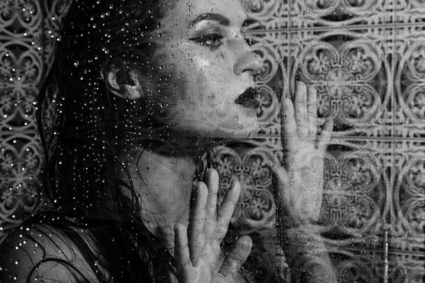 通过湿玻璃捕捉的美丽而感性的女人的肖像图片下载