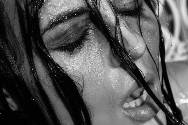 悲伤和潮湿的女人，她的脸上涂着污浊的化妆品在淋浴下图片下载