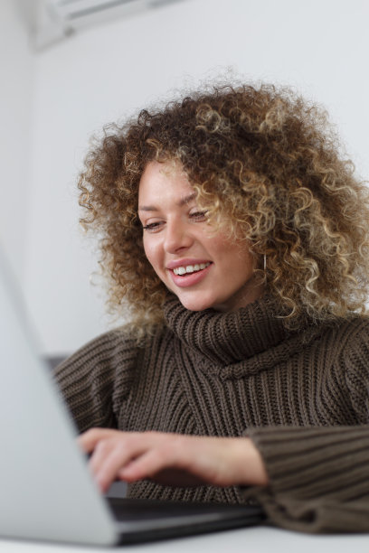 快乐的年轻女子在家里的笔记本电脑上打字。女程序员在笔记本电脑上编程图片下载