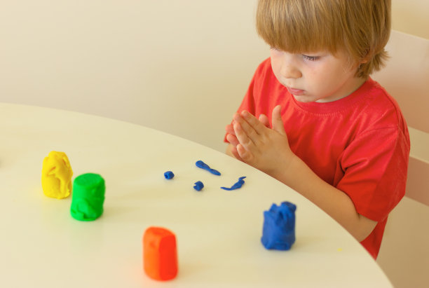 小男孩坐在桌子旁用橡皮泥雕刻。童年，为孩子发展活动。图片下载