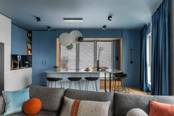 厨房内部设计:大理石厨房岛，黑色颈链，蓝色厨房家具，现代灯具，窗户，灰色沙发，彩色枕头和个人配件。家居装饰。模板。图片下载