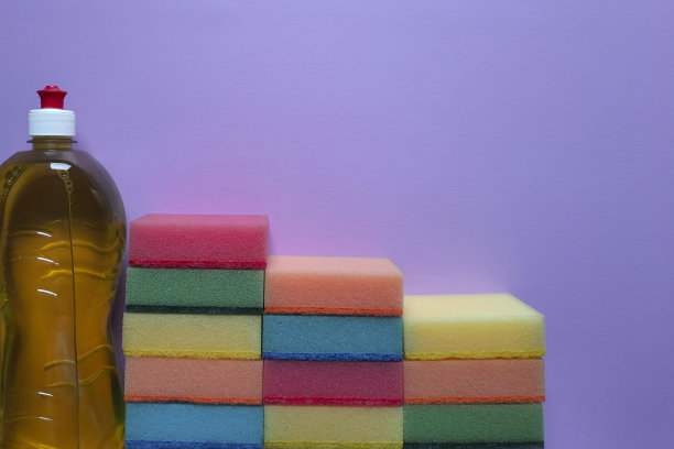 步骤由多色厨房清洁海绵和洗涤剂在紫色的背景与地方文字。图片下载