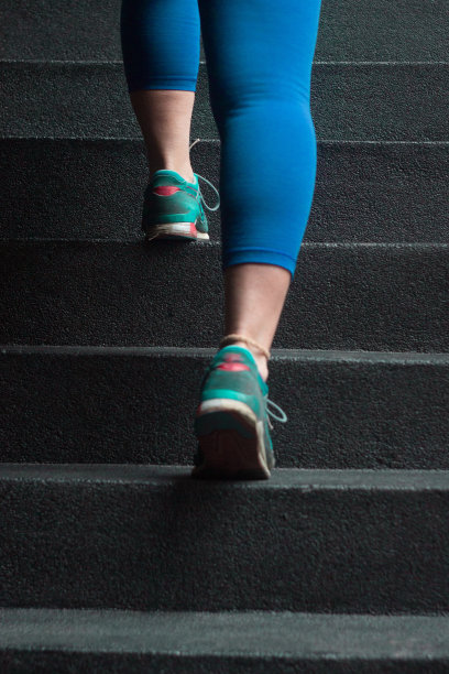 一个运动女性在紧身裤和运动鞋锻炼和爬楼梯的背影图片下载