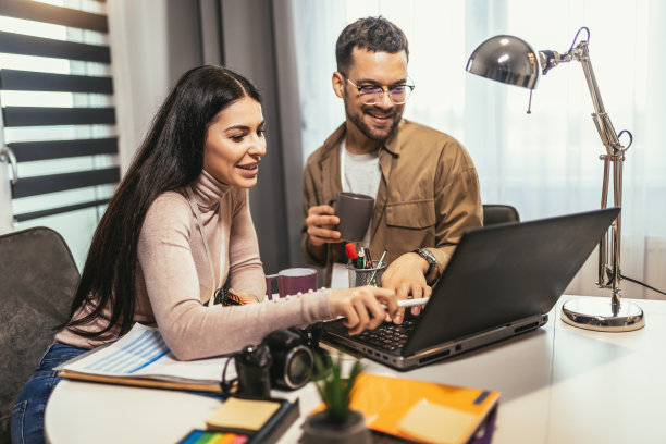 年轻的一对摄影师在工作场所用笔记本电脑工作，在工作室用电脑工作图片下载