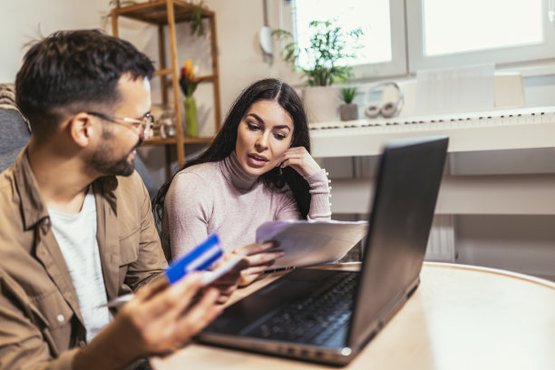 年轻夫妇一起付账单，客户在网上用信用卡支付，坐在家里舒适的客厅里图片下载