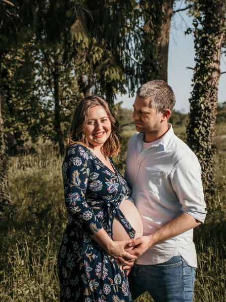 一对年轻漂亮的夫妇要生孩子了。幸福的父母站在公园的户外照片。图片下载