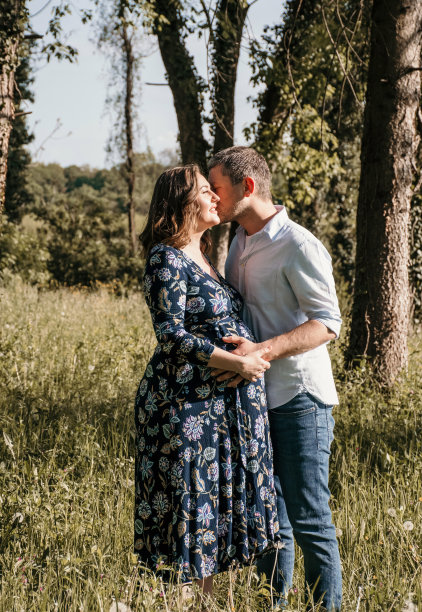 一对年轻漂亮的夫妇要生孩子了。幸福的父母站在公园的户外照片。图片下载