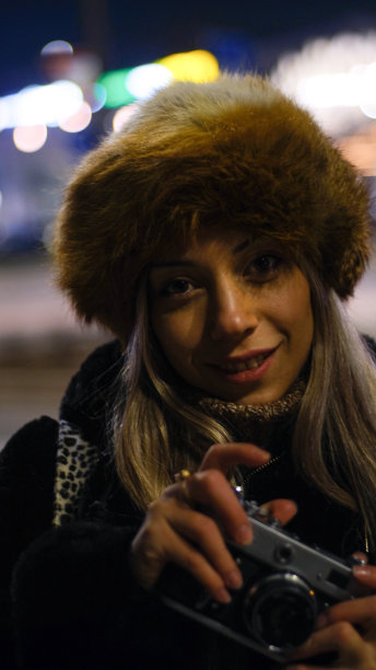 年轻女子在街上用模拟复古相机拍照图片下载