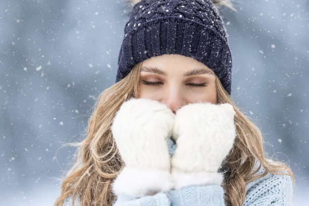 在寒冷的冬天，穿着暖和衣服的女孩在寒冷的户外颤抖。图片下载