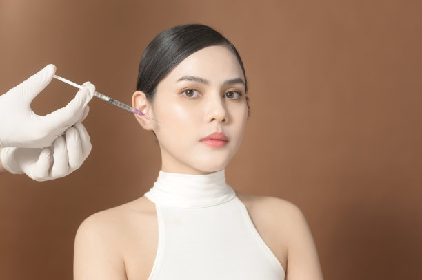 画像美丽的年轻女子脸和医生手戴手套手持注射器，面部美容注射概念图片下载