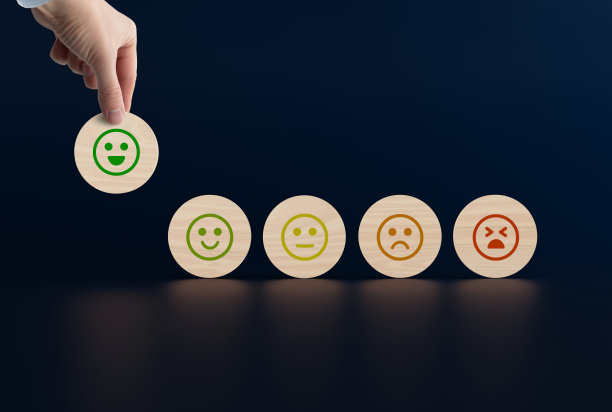 木制的圆盘上有从快乐到悲伤的面孔图标，一只手拿起一个有图标的圆盘。图片下载