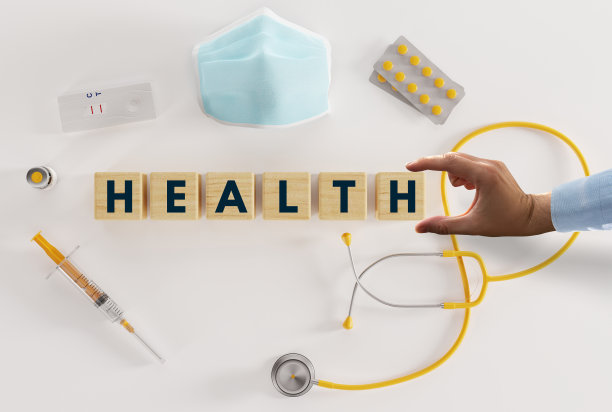 各种医疗设备，如注射器、听诊器、口罩、药片和用手放置的印有“健康”字样的木块。图片下载