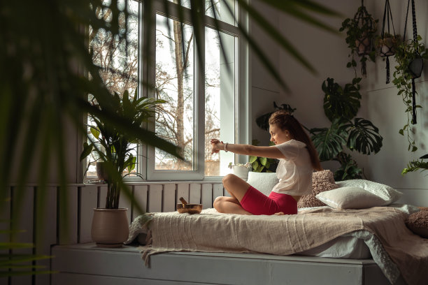 年轻的运动女子在家里练习瑜伽，坐在莲花的位置。放松和冥想。健康，幸福，心理健康的概念。图片下载