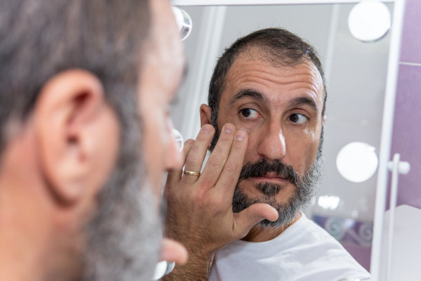 成熟的白人男子在镜子前涂面霜图片下载